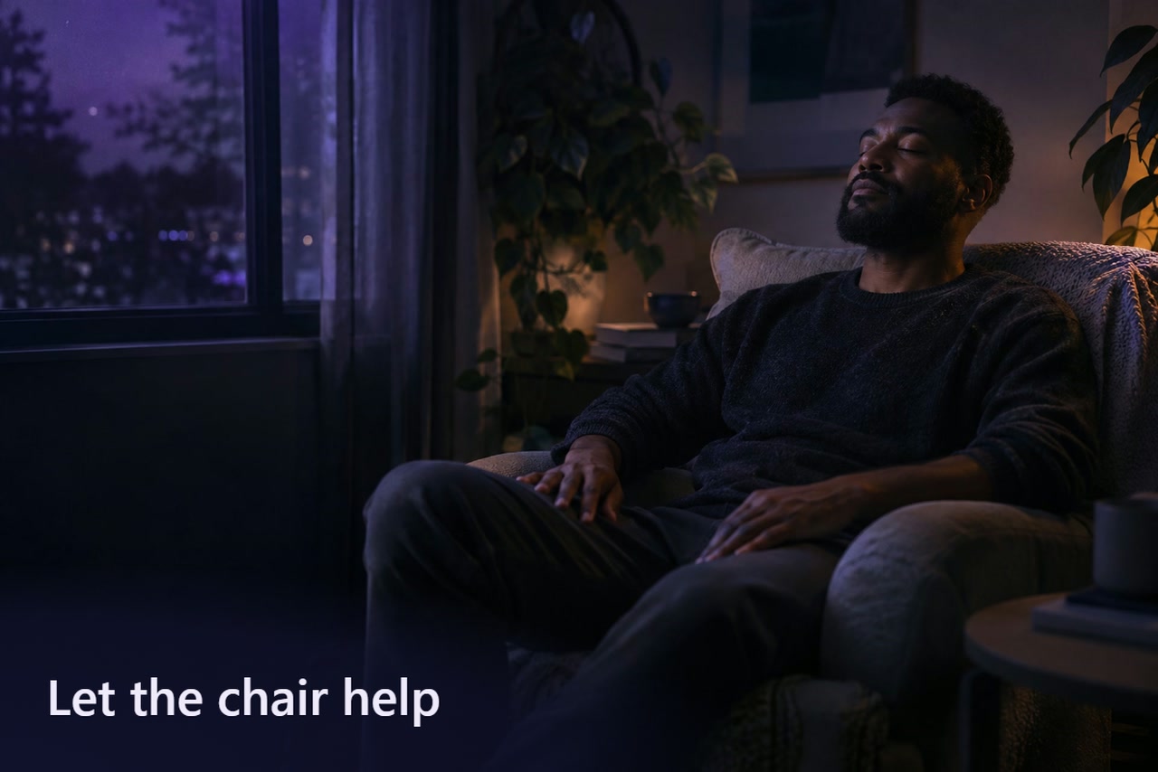 A man sits with eyes closed and hands resting on his thighs in an armchair beside a violet-lit window.