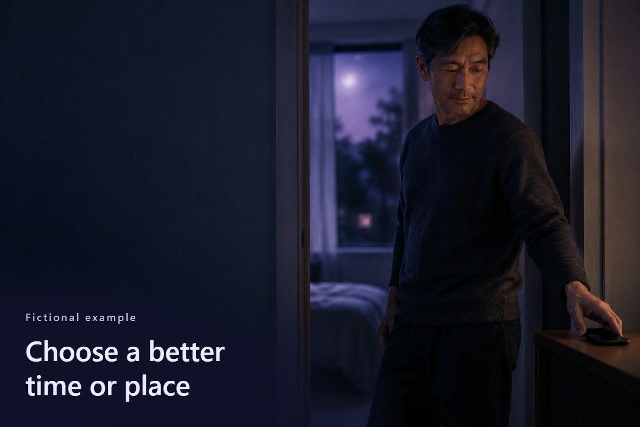 A man in a doorway sets a dark phone on a small table.
