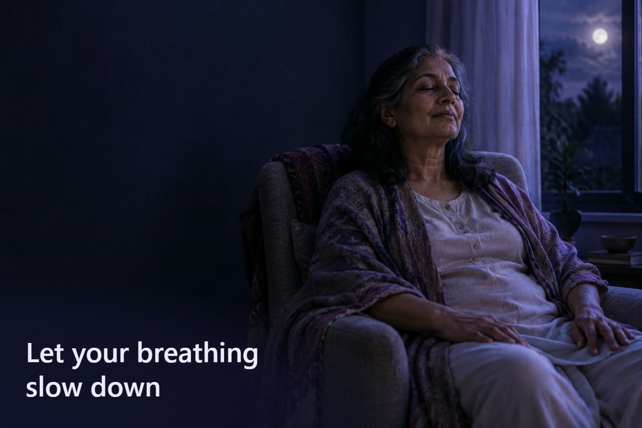 An older woman sits in an armchair with her hands resting on her thighs.